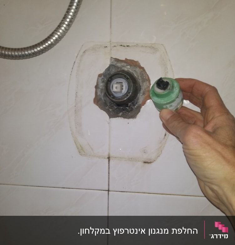 יד מחזיקה חלק אינסטלציה ליד קיר עם צינור מתכת